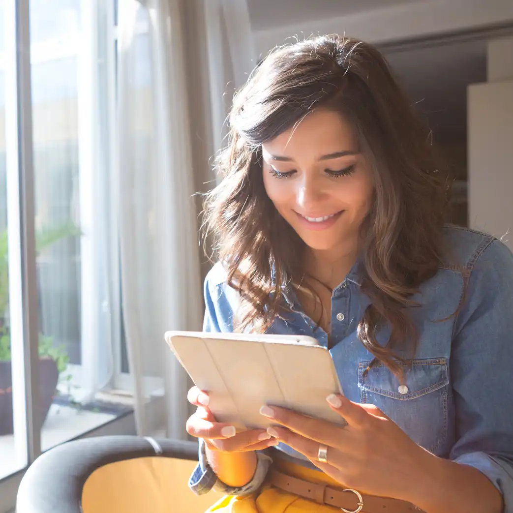 A woman holding a tablet and smiling