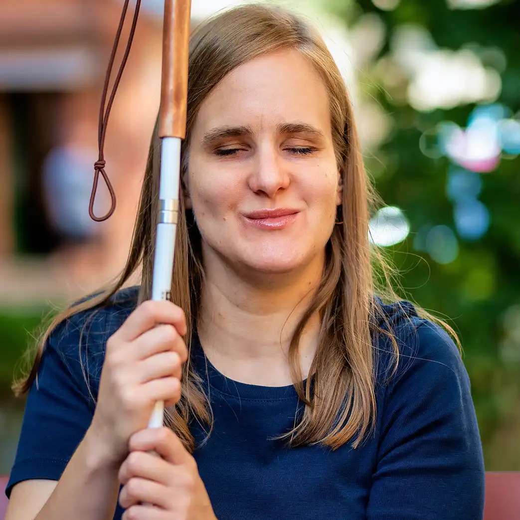 Blind woman smiling and holding her white cane