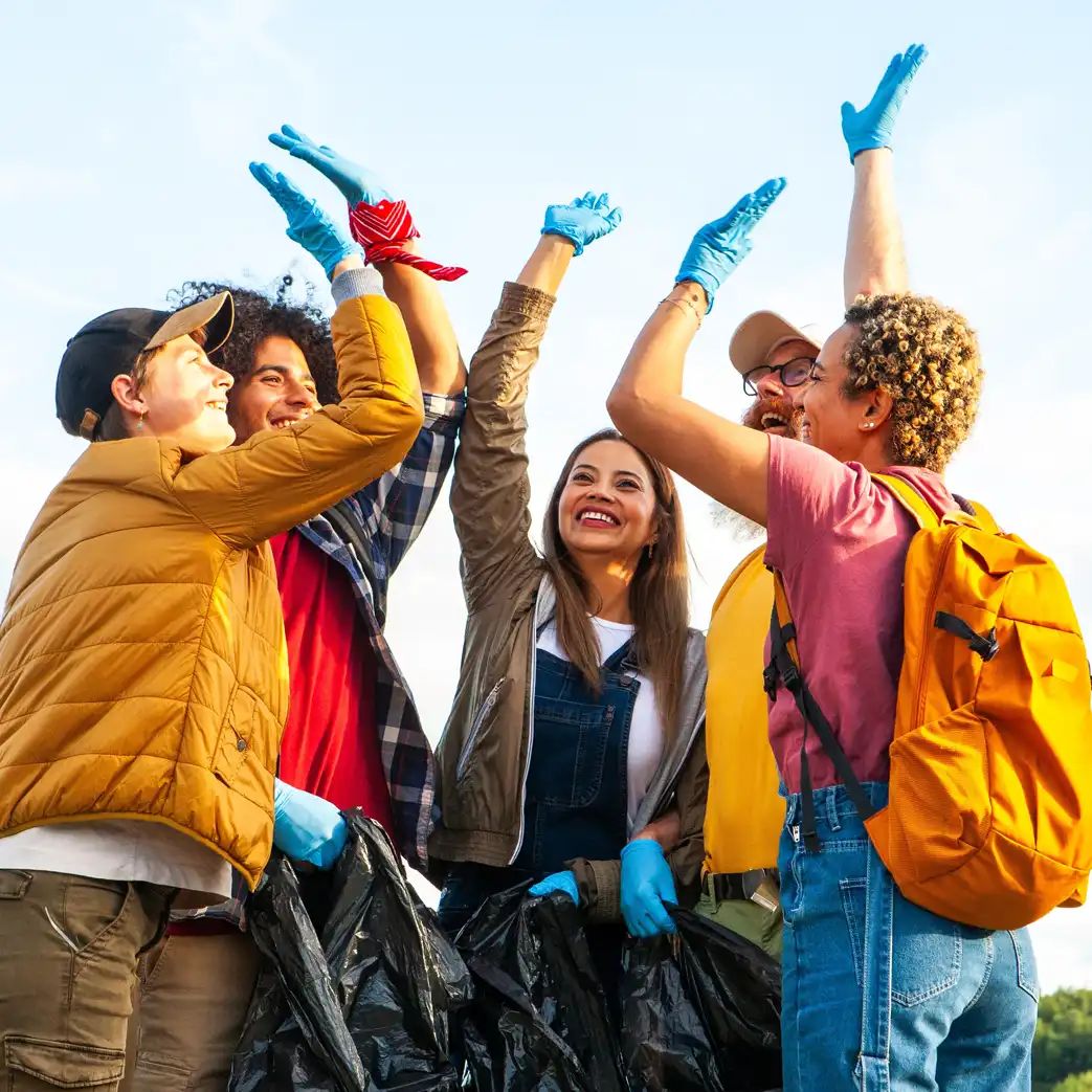 A group of people doing community service volunteering and are in the middle of a group high-five